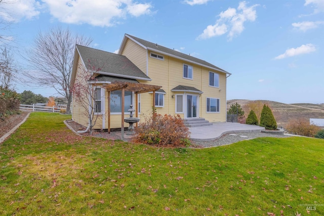 back of house with a lawn, a patio area, and a hot tub