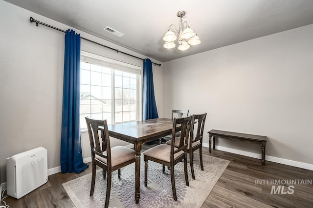 dining space featuring baseboards, visible vents, a notable chandelier, and wood finished floors