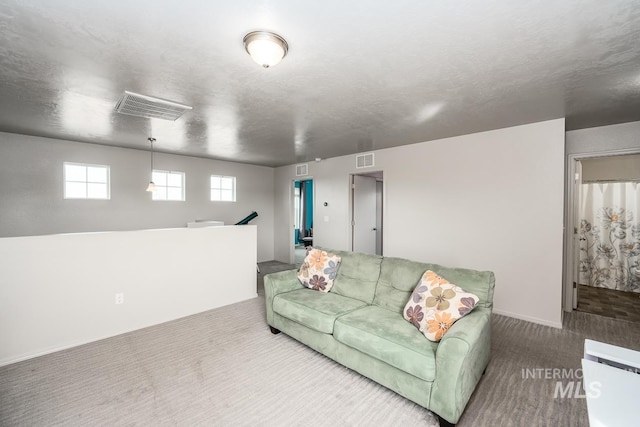 carpeted living area with visible vents and a textured ceiling