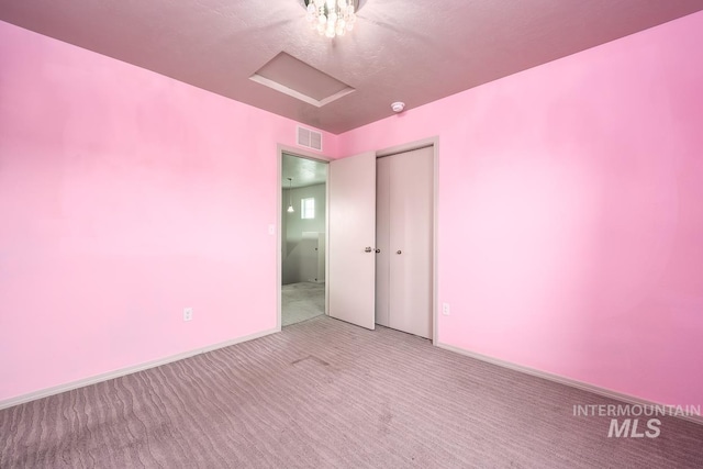 empty room featuring visible vents, carpet flooring, attic access, and baseboards