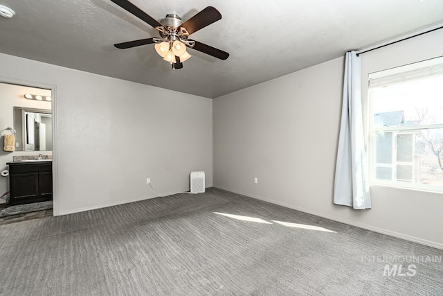 unfurnished bedroom featuring carpet floors, a sink, baseboards, and a ceiling fan