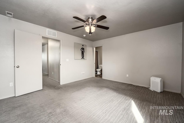 unfurnished room featuring carpet, visible vents, ceiling fan, and a textured ceiling