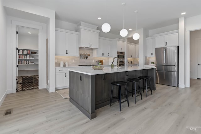 125 S Eagles Roost Way, Eagle, ID 83616 - kitchen with stainless steel appliances, light wood finished floors, white cabinets, light countertops, and recessed lighting