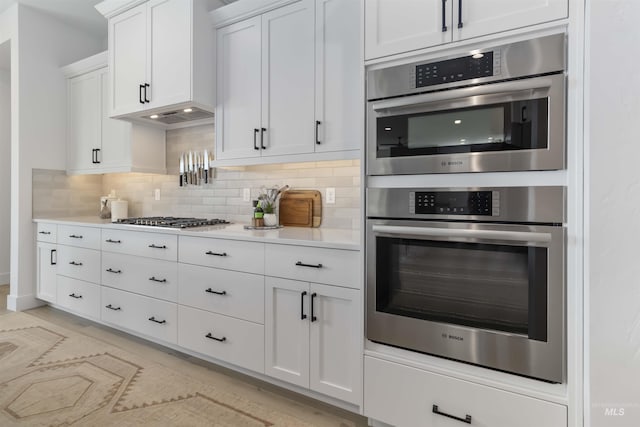 125 S Eagles Roost Way, Eagle, ID 83616 - kitchen featuring appliances with stainless steel finishes, light countertops, backsplash, and white cabinets