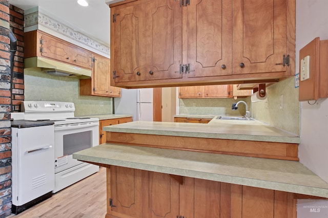 kitchen with a sink, white appliances, light countertops, a peninsula, and under cabinet range hood