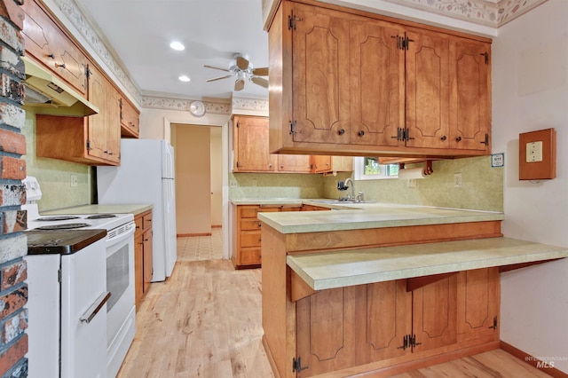 kitchen with a peninsula, white appliances, light wood-type flooring, light countertops, and a sink