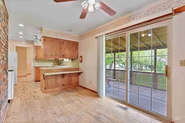 kitchen featuring ceiling fan, light countertops, a peninsula, baseboards, and light wood-type flooring