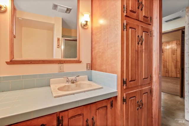 bathroom with an enclosed shower, concrete flooring, visible vents, and vanity