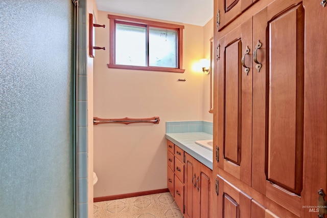 full bathroom with vanity, baseboards, and a shower with shower door