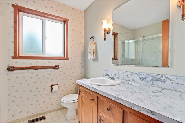 bathroom featuring vanity, toilet, wallpapered walls, visible vents, and a stall shower