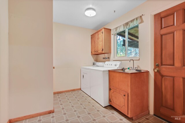 laundry area featuring baseboards, light floors, a sink, cabinet space, and independent washer and dryer