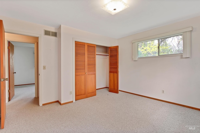 unfurnished bedroom with visible vents, baseboards, a closet, and light colored carpet