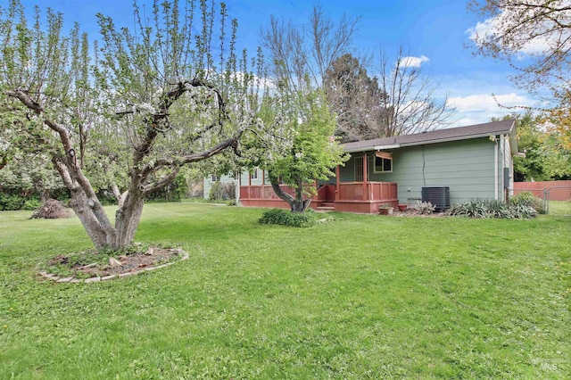 view of yard with cooling unit, a wooden deck, and fence