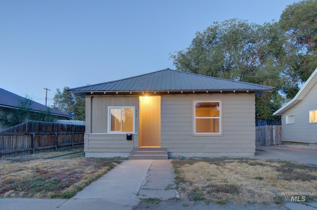 bungalow with entry steps, metal roof, and fence