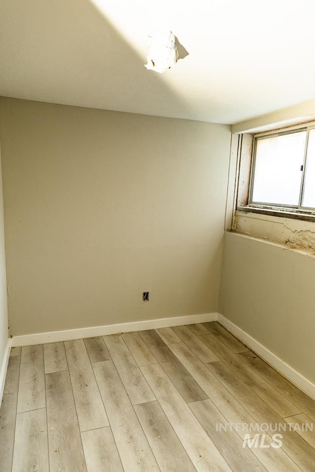 unfurnished room with baseboards and light wood-style flooring