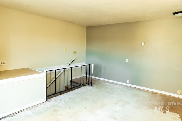 empty room featuring unfinished concrete flooring and baseboards