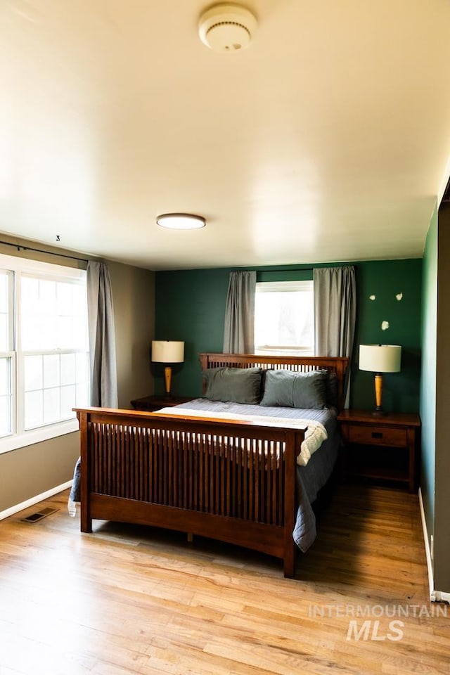 bedroom featuring wood finished floors, visible vents, and baseboards