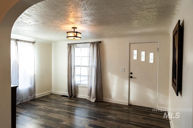 entrance foyer with baseboards, arched walkways, a textured ceiling, and dark wood-style flooring