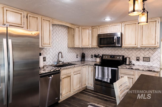 kitchen featuring a sink, light stone countertops, light brown cabinetry, stainless steel appliances, and dark wood-style flooring