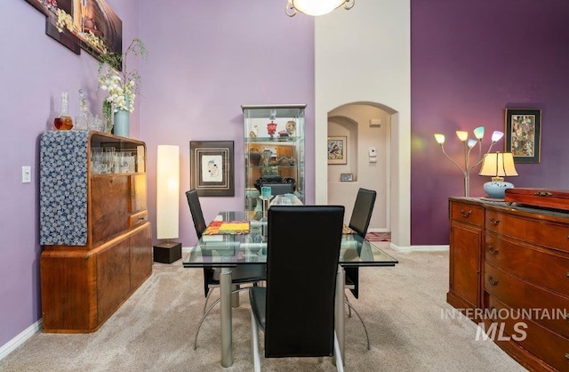 dining room with light carpet and a towering ceiling