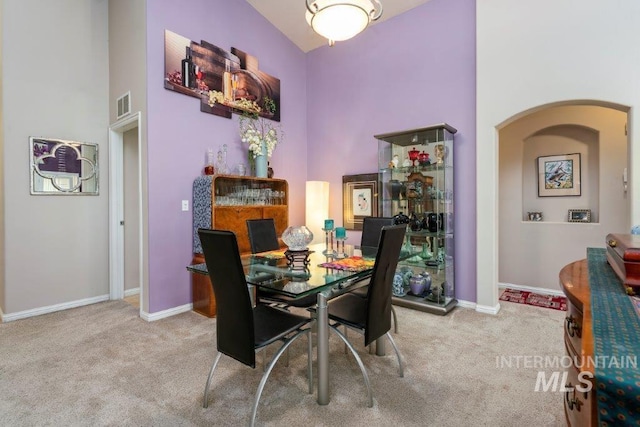 dining room featuring light carpet and a towering ceiling