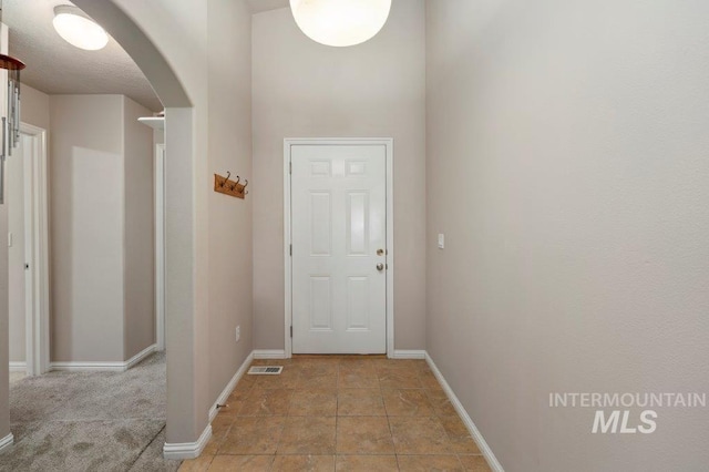 doorway with a textured ceiling and light tile patterned floors