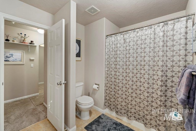 bathroom with toilet, a textured ceiling, a shower with curtain, and tile patterned flooring