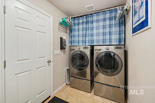 laundry area featuring a textured ceiling and washer and clothes dryer