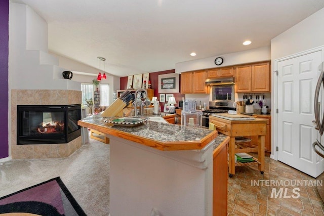 kitchen with stainless steel gas stove, light carpet, a multi sided fireplace, sink, and pendant lighting