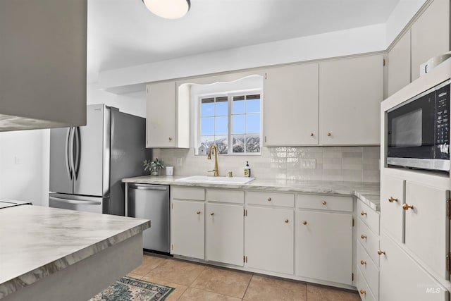 kitchen featuring sink, light tile patterned floors, white cabinetry, stainless steel appliances, and decorative backsplash