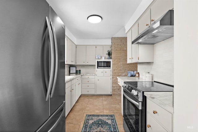 kitchen with appliances with stainless steel finishes, light tile patterned floors, decorative backsplash, and exhaust hood