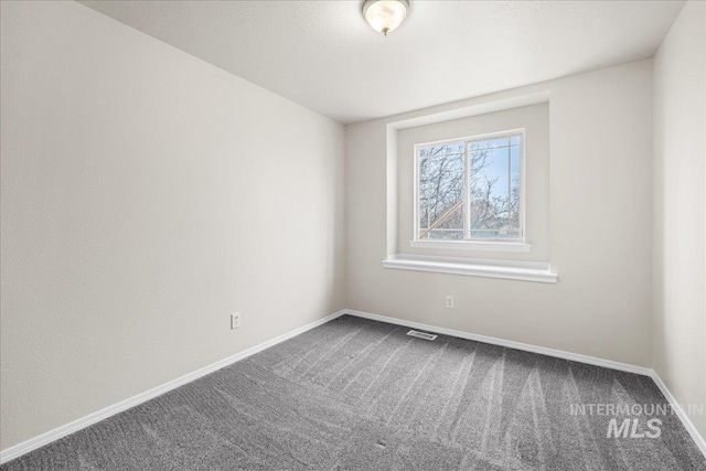 carpeted spare room featuring visible vents and baseboards