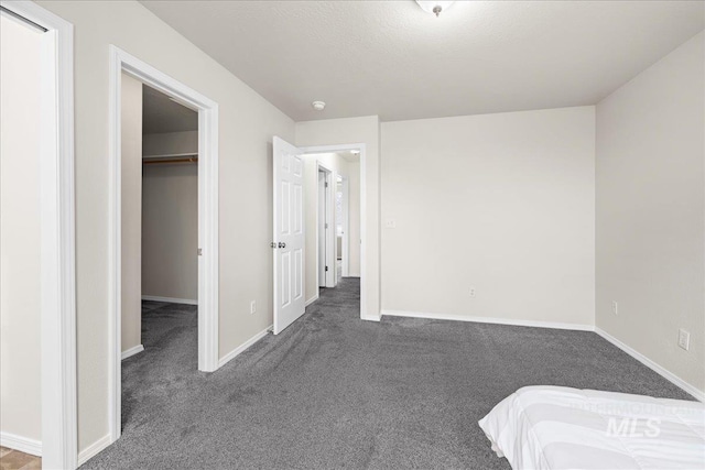 unfurnished bedroom featuring a spacious closet, carpet, and baseboards