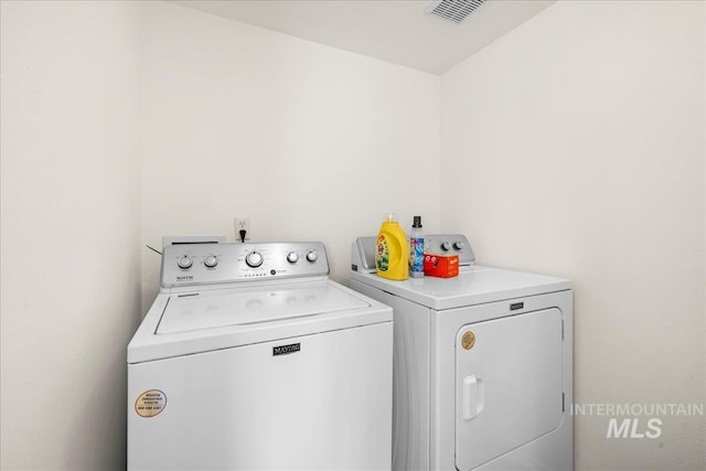 washroom with visible vents, laundry area, and washing machine and clothes dryer