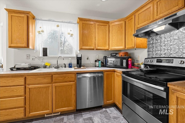 kitchen with visible vents, under cabinet range hood, light countertops, stainless steel appliances, and a sink