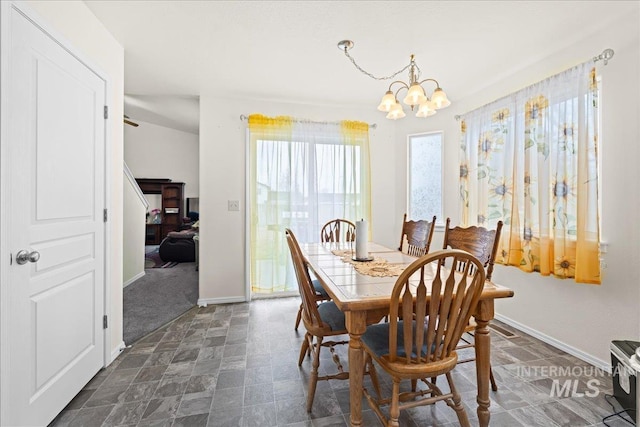 dining room featuring a notable chandelier, baseboards, and stone finish flooring