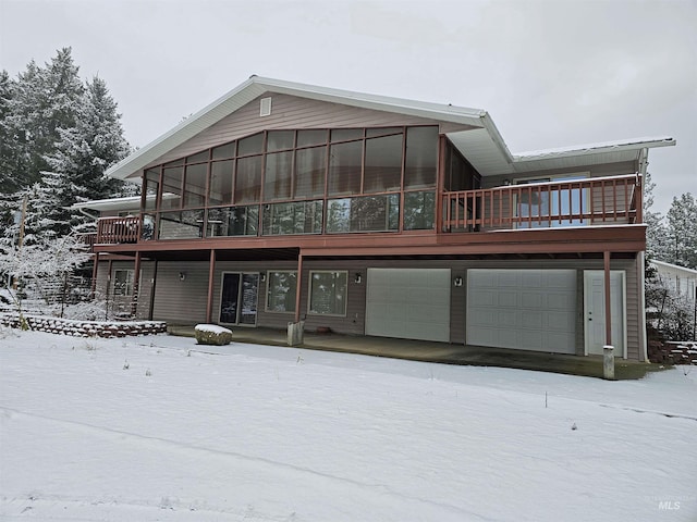 snow covered back of property with a garage