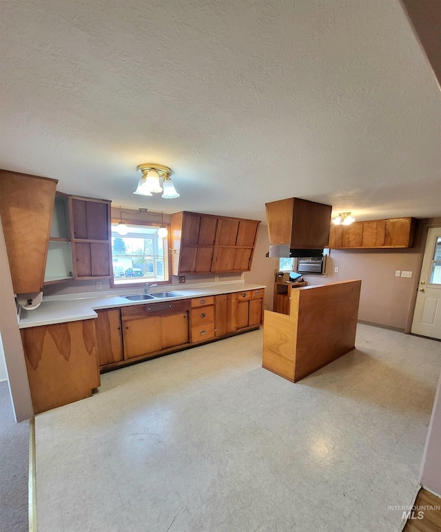 kitchen with a textured ceiling, kitchen peninsula, and sink