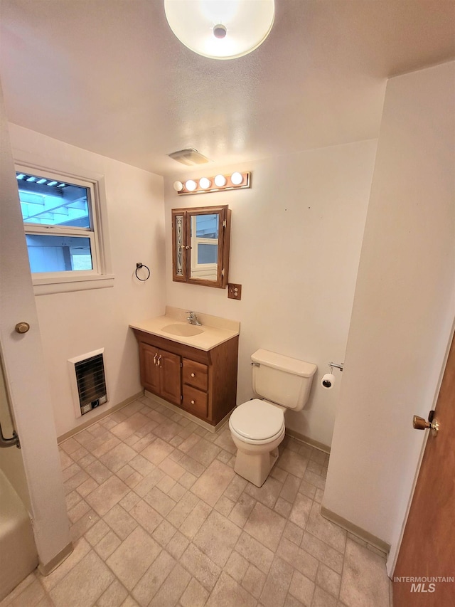 bathroom featuring heating unit, vanity, and toilet