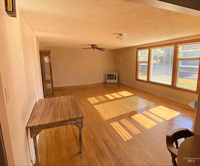 interior space with heating unit, ceiling fan, a textured ceiling, and light hardwood / wood-style flooring