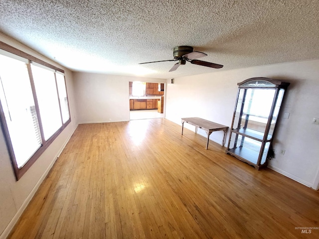 unfurnished living room with ceiling fan, a textured ceiling, and light wood-type flooring