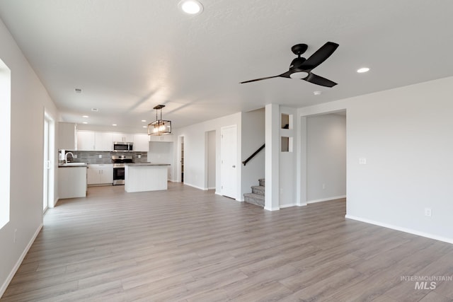 unfurnished living room with sink, light hardwood / wood-style floors, and ceiling fan