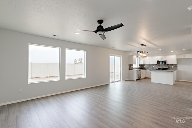 unfurnished living room featuring sink, ceiling fan, and light hardwood / wood-style floors