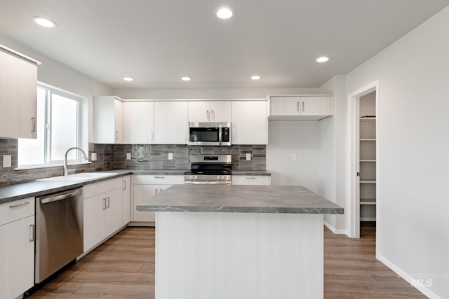 kitchen with sink, white cabinetry, a kitchen island, light hardwood / wood-style floors, and stainless steel appliances