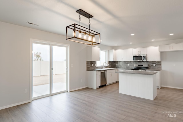 kitchen featuring a center island, appliances with stainless steel finishes, white cabinets, sink, and pendant lighting