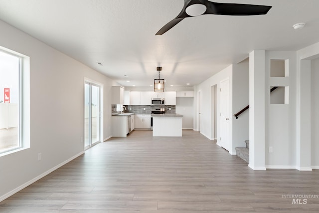 unfurnished living room featuring ceiling fan, sink, light wood-type flooring, and a wealth of natural light