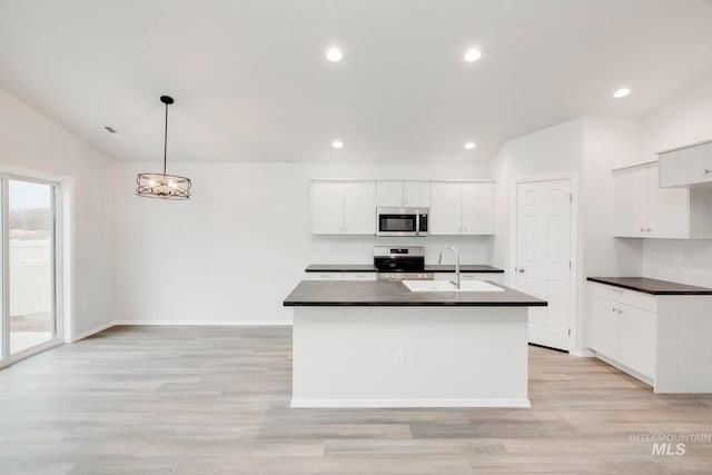 kitchen featuring decorative light fixtures, white cabinetry, stainless steel appliances, and vaulted ceiling