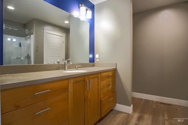 bathroom featuring wood-type flooring, a shower, and vanity