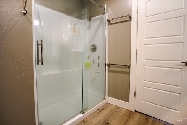 bathroom featuring hardwood / wood-style flooring and a shower with shower door