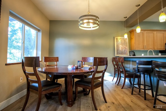 dining area featuring an inviting chandelier, light wood-type flooring, and sink